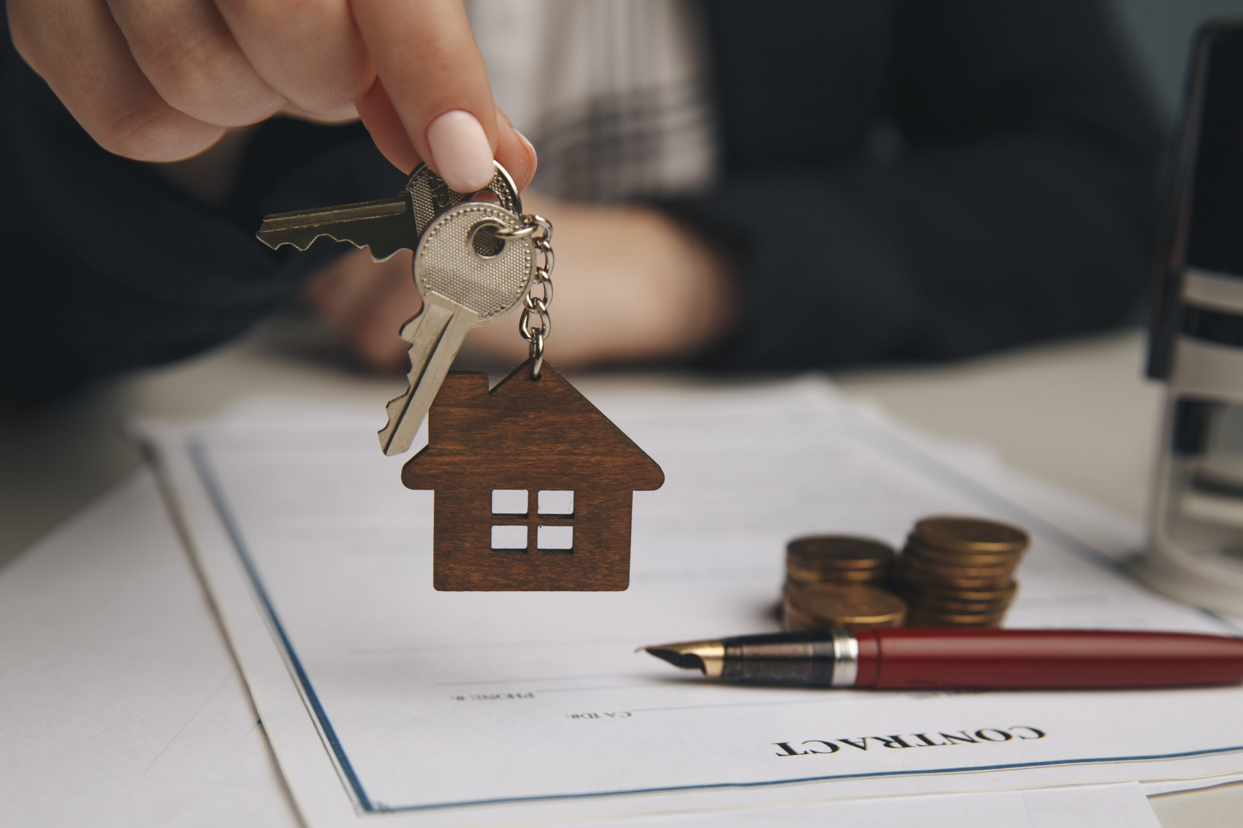 Close up wooden toy house with Woman signs a purchase contract or mortgage for a home, Real estate concept.